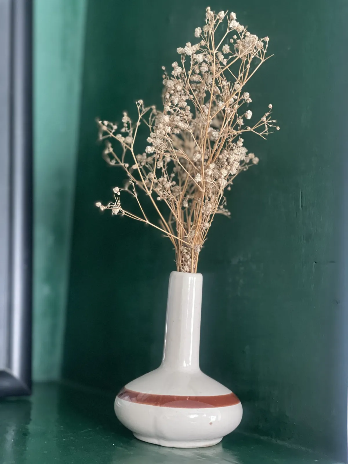 Dried white flowers in a cream vase with a terracotta stripe